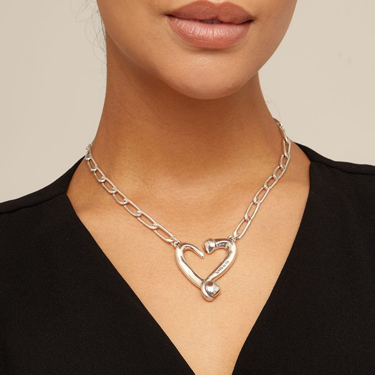 Silver heart necklace on a person, complementing a black top.